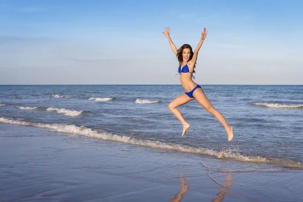 Giovane donna allegra in bikini che salta sulla spiaggia . — Foto Stock