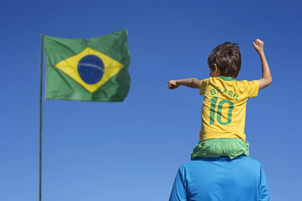 Menino e seu pai olhando para a bandeira brasileira — Fotografia de Stock