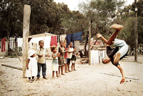Мальчик прыгает, делает сальто в городке, Южная Африка
.