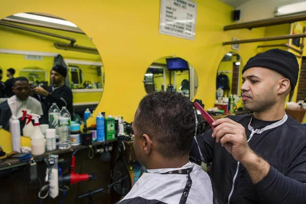 Peluquero dando a su cliente un corte de pelo, en la peluquería . — Foto de Stock