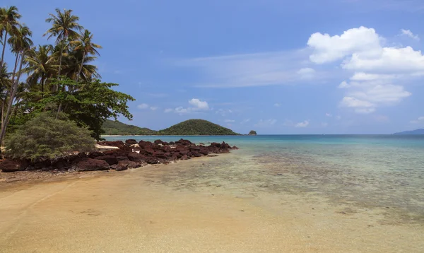 Пальмы на пляже со скалами и островами — стоковое фото