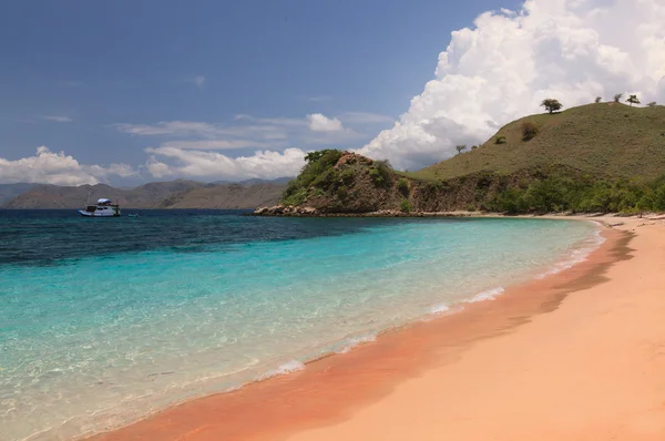 Playa rosa y mar turquesa con una isla de montaña en Indonesia — Foto de Stock