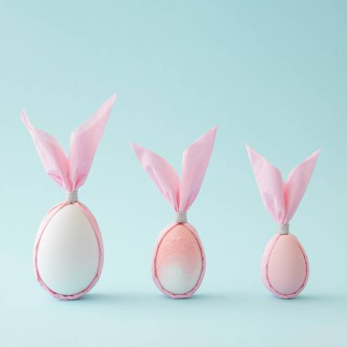 Pastel mavi arka planda tavşan şeklinde paskalya pembesi yumurtaları. Yaratıcı asgari bileşim.