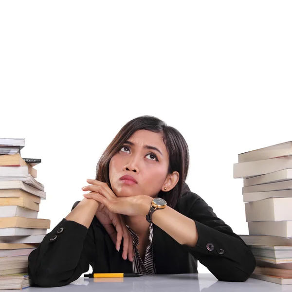 Mujer frustrada se sienta en pilas de libros mirando hacia arriba — Foto de Stock