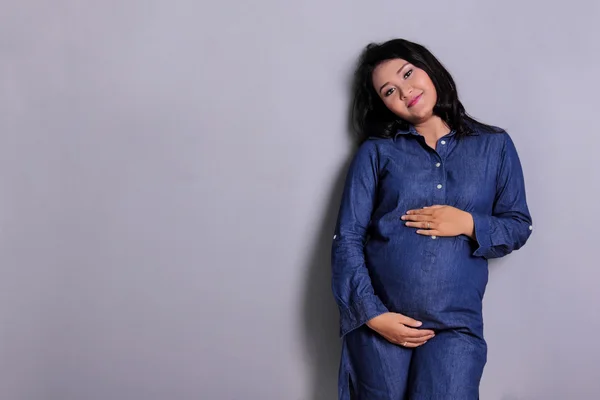 Mujer embarazada relajándose en la pared gris —  Fotos de Stock