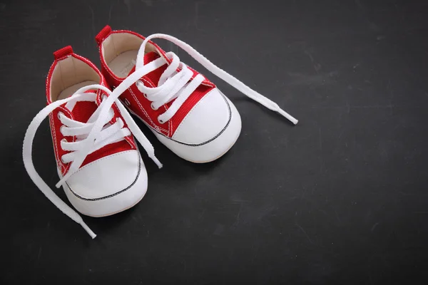 Small child shoes on blackboard — Stock Photo, Image