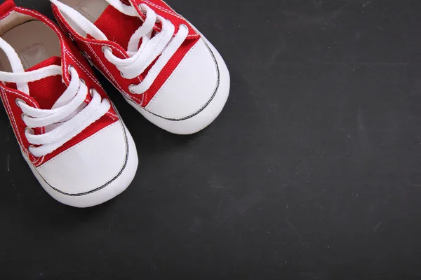 Red canvas shoes in the corner of blackboard — Stock Photo, Image