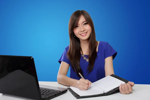Щасливі азіатських брюнетки писати на ноутбук і посміхається на камеру — стокове фото