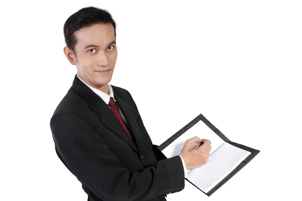 Empresario escribiendo en cuaderno y mirando a cámara, aislado — Foto de Stock