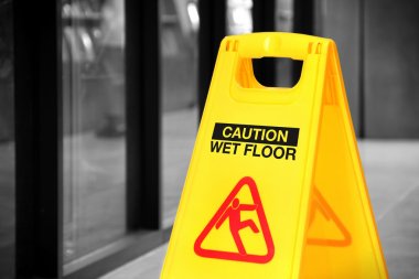 Yellow wet floor sign in a hallway, selective color clipart