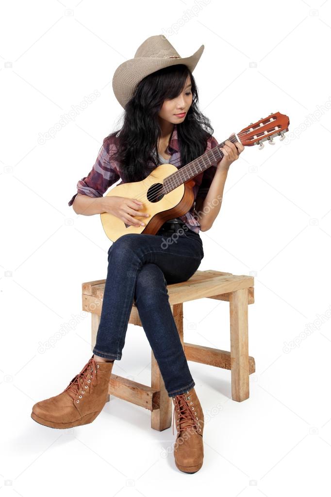 Cowgirl plays ukulele on a chair