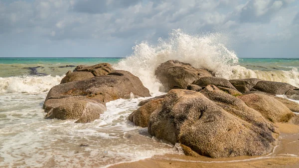 Onde del mare che si infrangono sulle rocce Foto Stock