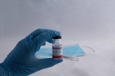 Kadın doktor elleri ellerinde bir aşı ve altına dayanmış bir çene kayışıyla.