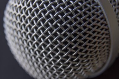 Bir mikrofona yakın çekim. Mikrofonun metalik üst kısmı ayrıntılı olarak gözlemlenir..