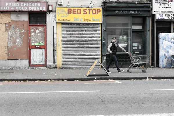 Мужчины на улице с тележкой супермаркета — стоковое фото