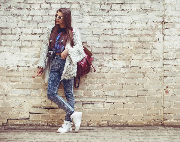 Menina de moda de rua jovem no fundo da parede de tijolo velho. Ao ar livre, estilo de vida . — Fotografia de Stock