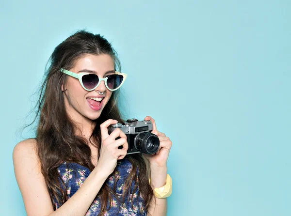 Moda mujer con estilo bailando y haciendo fotos con cámara retro. Retrato sobre fondo azul en suéter blanco — Foto de Stock