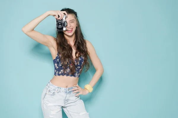 Moda mujer con estilo bailando y haciendo fotos con cámara retro. Retrato sobre fondo azul en suéter blanco — Foto de Stock