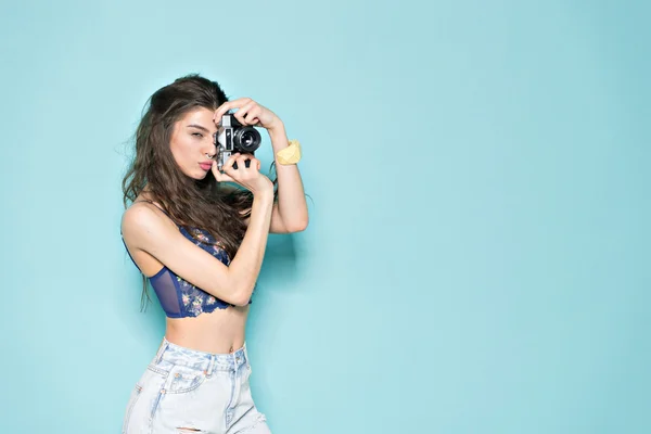 Moda mujer con estilo bailando y haciendo fotos con cámara retro. Retrato sobre fondo azul en suéter blanco —  Fotos de Stock