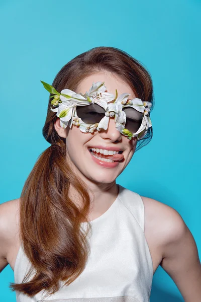 Retrato de moda de una hermosa joven con gafas de sol de flores sobre fondo azul — Foto de Stock