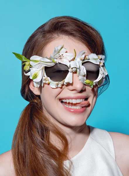 Retrato de moda de una hermosa joven con gafas de sol de flores sobre fondo azul — Foto de Stock