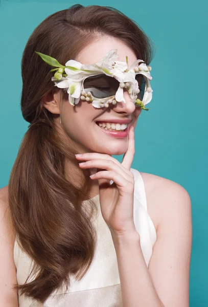 Fashion portrait of beautiful young lady with flowers sunglasses on blue background