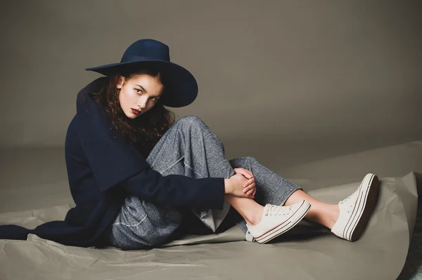 Modelo de moda mujer abrigo y sombrero estilo urbano pose sobre fondo de color en estudio — Foto de Stock