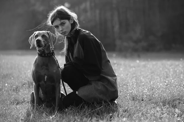 Fille de mode modèle marcher avec son chien plein air parc nature arrière-plan — Photo