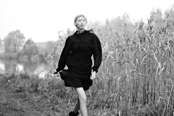 Fashion model woman run in black dress. Nature background.