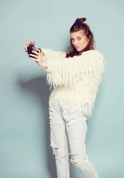 Moda mujer con estilo bailando y haciendo fotos con cámara retro. Retrato sobre fondo azul en suéter blanco —  Fotos de Stock