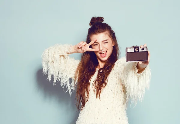 Moda mujer con estilo bailando y haciendo fotos con cámara retro. Retrato sobre fondo azul en suéter blanco — Foto de Stock