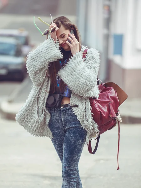 Femme gaie parlant au téléphone dans la rue portant un manteau gris  . — Photo