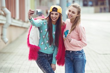 Hippi kız arkadaşlarım an modern smartphone ile eternalizing bir selfie - dostluk ve yeni trendler ve teknoloji ile eğlenceli kavramı - kentsel şehir bağlamda alarak