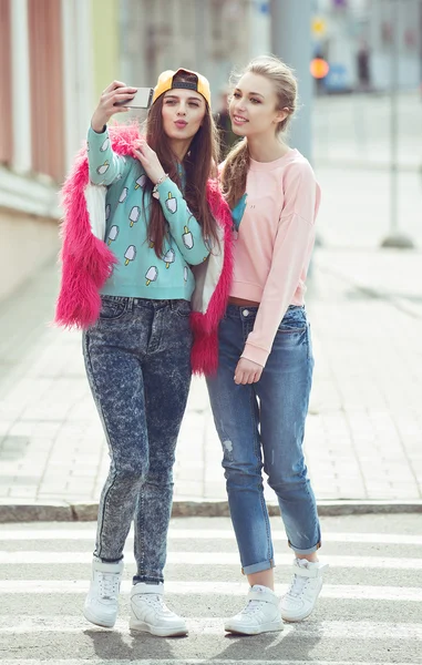 Novias Hipster tomando una selfie en el contexto urbano de la ciudad - Concepto de amistad y diversión con nuevas tendencias y tecnología - Mejores amigos eternizando el momento con un teléfono inteligente moderno — Foto de Stock