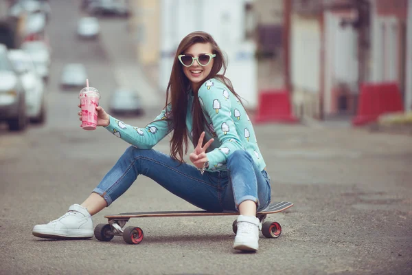 güzel bir genç kadın bir kaykay, gün batımında moda yaşam tarzı ile poz