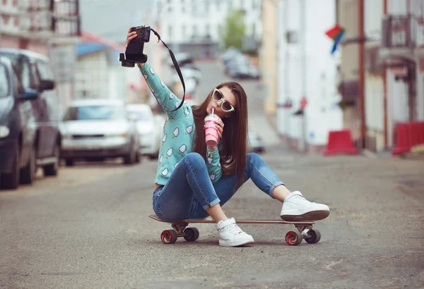 Bella giovane donna in posa con uno skateboard, stile di vita alla moda al tramonto — Foto Stock