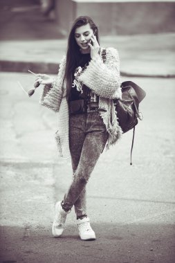 Gri bir ceket giyen sokakta telefonda konuşan neşeli kadın .