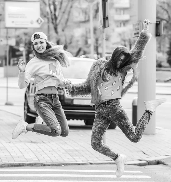 Modieuze mooie jonge vriendinnen permanent samen in de buurt van een blauwe achtergrond. Twee blondjes en een brunette. Gelet grappig en poseren. Binnen. Afgezwakt in warme kleuren — Stockfoto