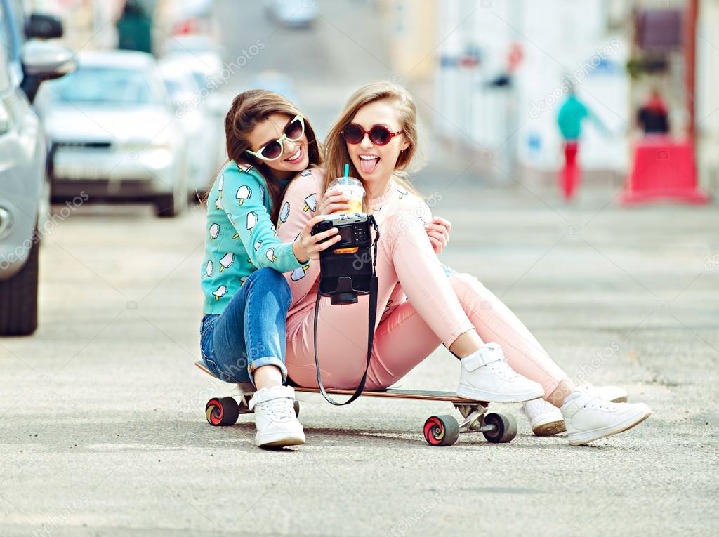 Hipster girlfriends taking a selfie in urban city context - Concept of friendship and fun with new trends and technology - Best friends eternalizing the moment with camera