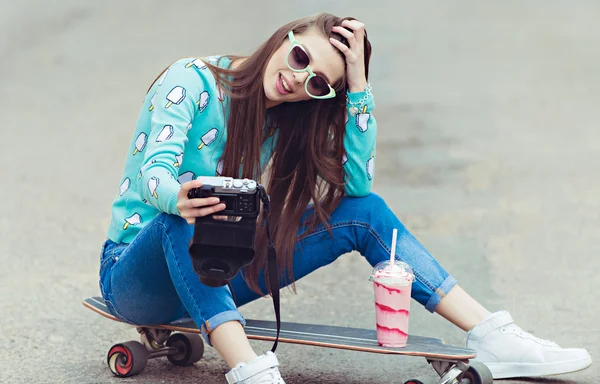 Mulher bonita posando com um skate, estilo de vida de moda ao pôr do sol — Fotografia de Stock