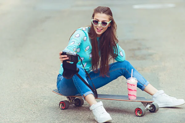 Schöne junge Frau posiert mit einem Skateboard, Mode-Lifestyle bei Sonnenuntergang — Stockfoto