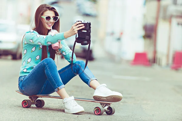 Mulher bonita posando com um skate, estilo de vida de moda ao pôr do sol — Fotografia de Stock
