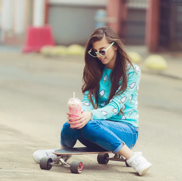 Mooie jonge vrouw poseren met een skateboard, mode levensstijl bij zonsondergang — Stockfoto