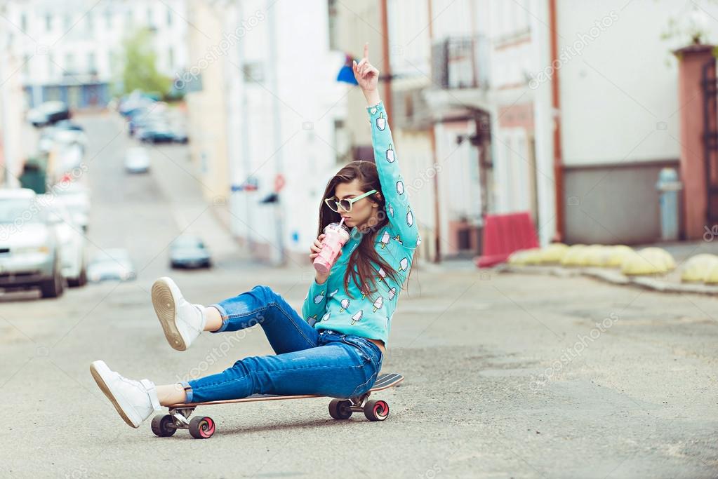 Beautiful young woman posing with a skateboard, fashion lifestyle at sunset