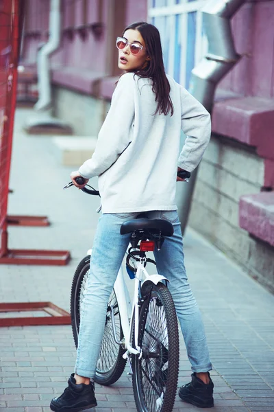 Retrato ao ar livre colorido de modelo de moda bonita jovem com bicicleta. Mulher sexy loira jovem posando no verão. Escola estilo menina . — Fotografia de Stock