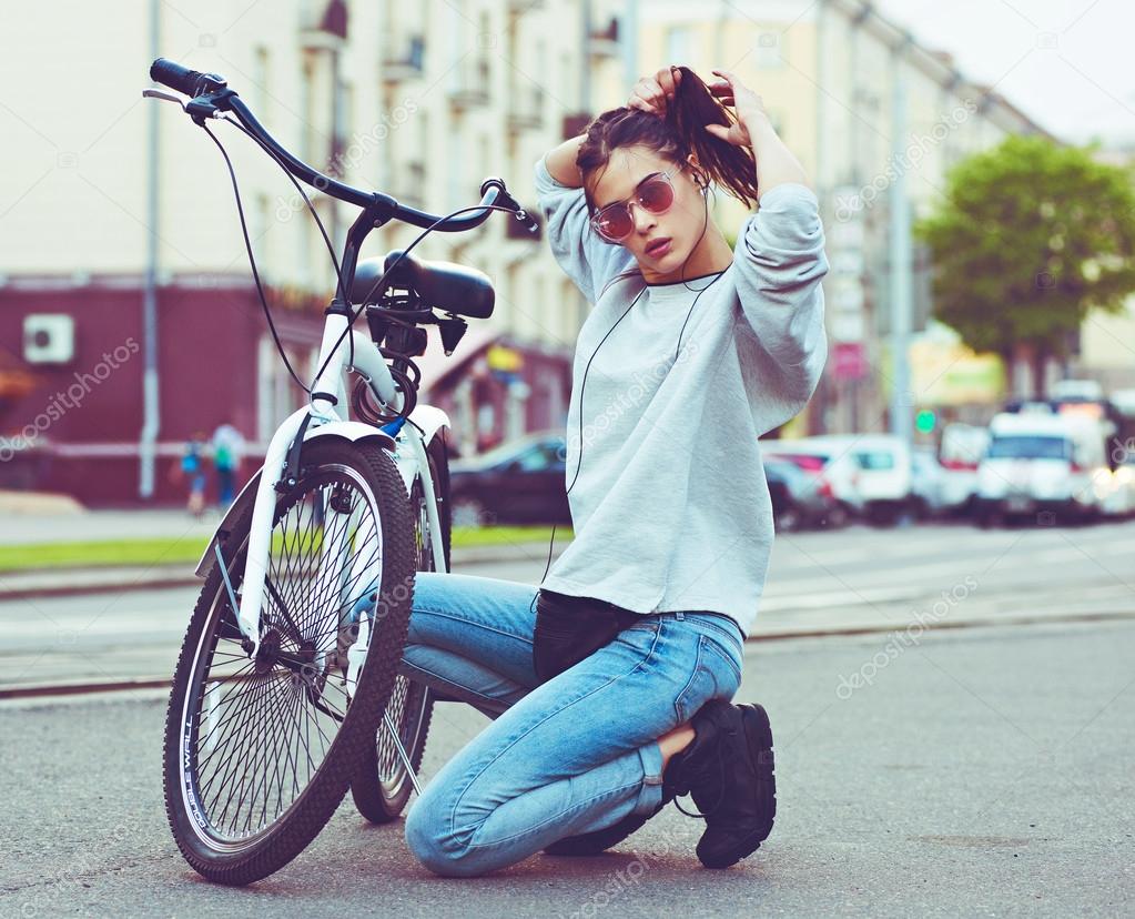 Colorful outdoor portrait of young pretty fashion model with bike. Young blonde sexy woman posing in summer. School girl style.