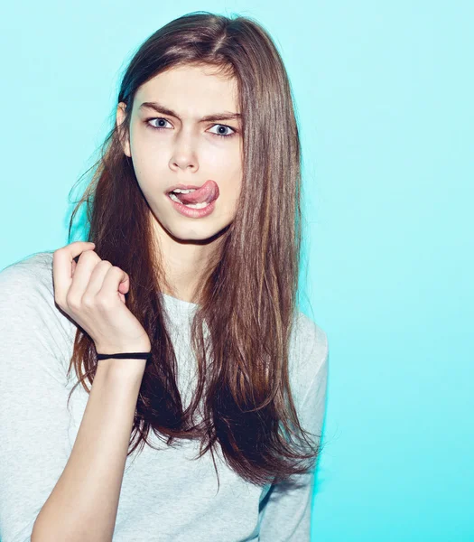 Emocjonalne hipster całkiem młoda dziewczyna zrobić śmieszną twarz na niebieskim tle — Zdjęcie stockowe