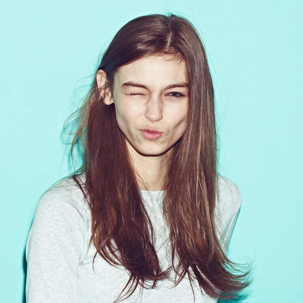 Érzelmi csípő csinos, fiatal lány, hogy vicces arc a kék háttér — Stock Fotó