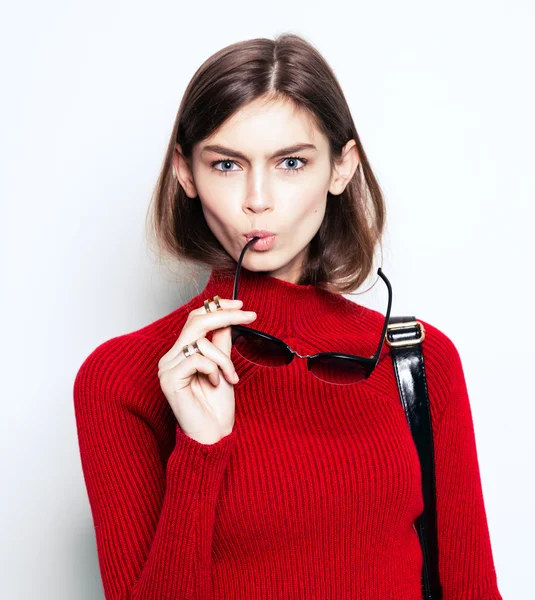 Fashion girl portrait in a stylish red sweater and sunglasses on a white background. Urban style — Stock Photo, Image