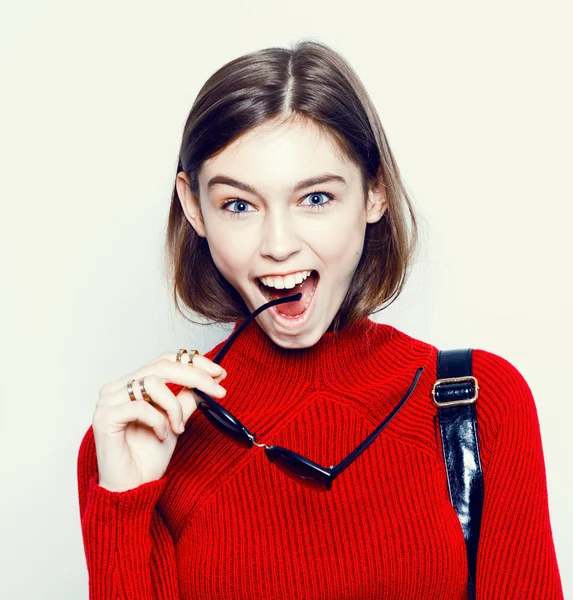 Fashion girl portrait in a stylish red sweater and sunglasses on a white background. Urban style — Stock Photo, Image